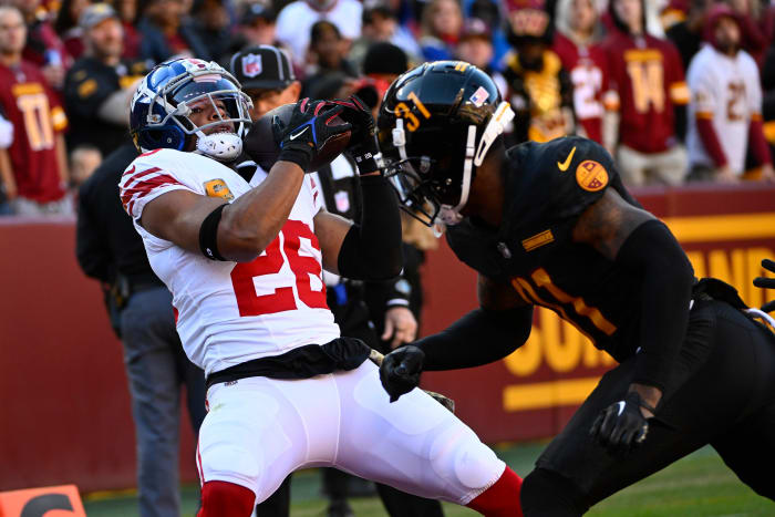 New York Giants running back Saquon Barkley (26) catches a touchdown past Washington Commanders safety Kamren Curl (31) during the first half at FedExField.